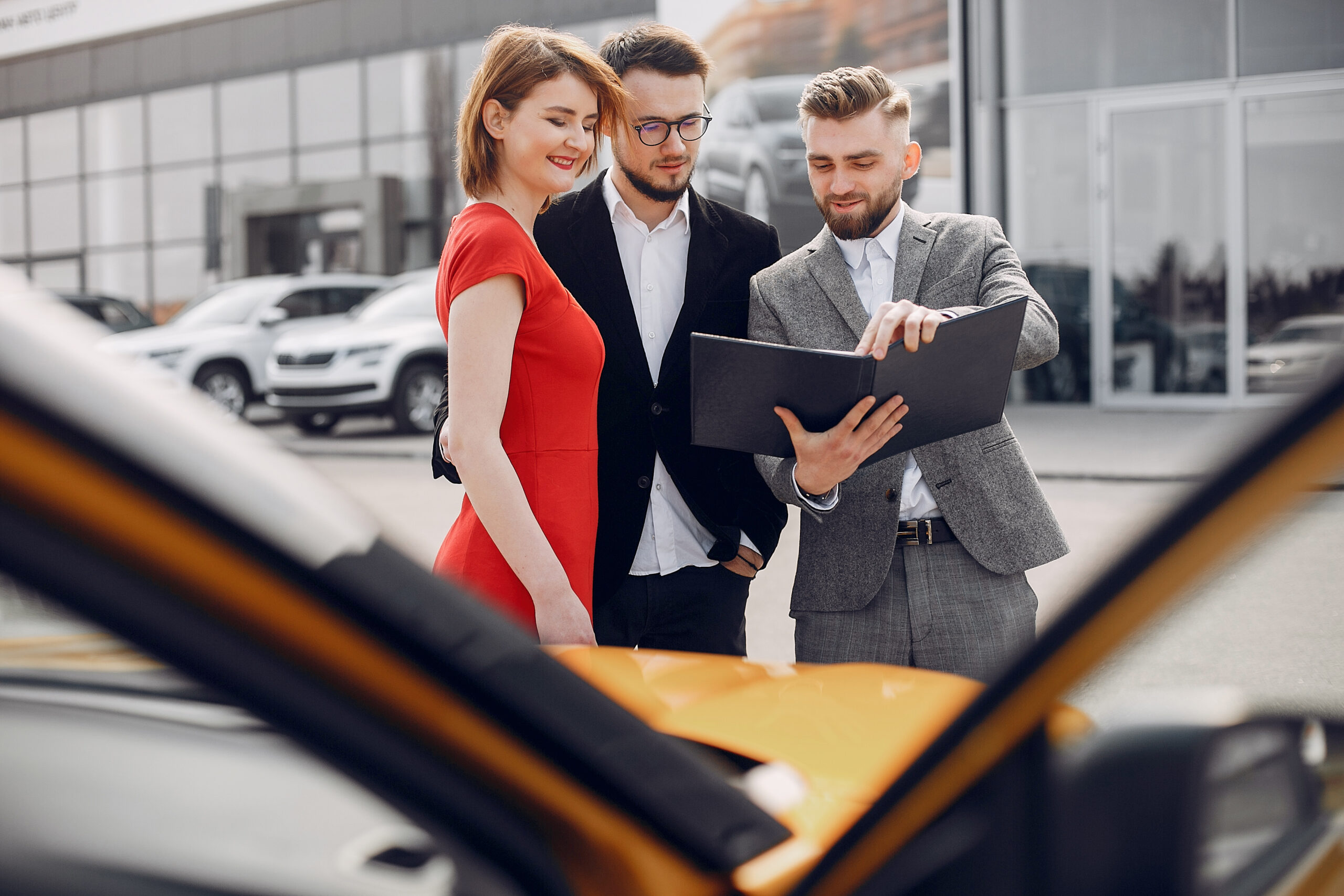 Couple in a car salon. Family buying the car. Elegant woman with her husband. Assistant with a clients