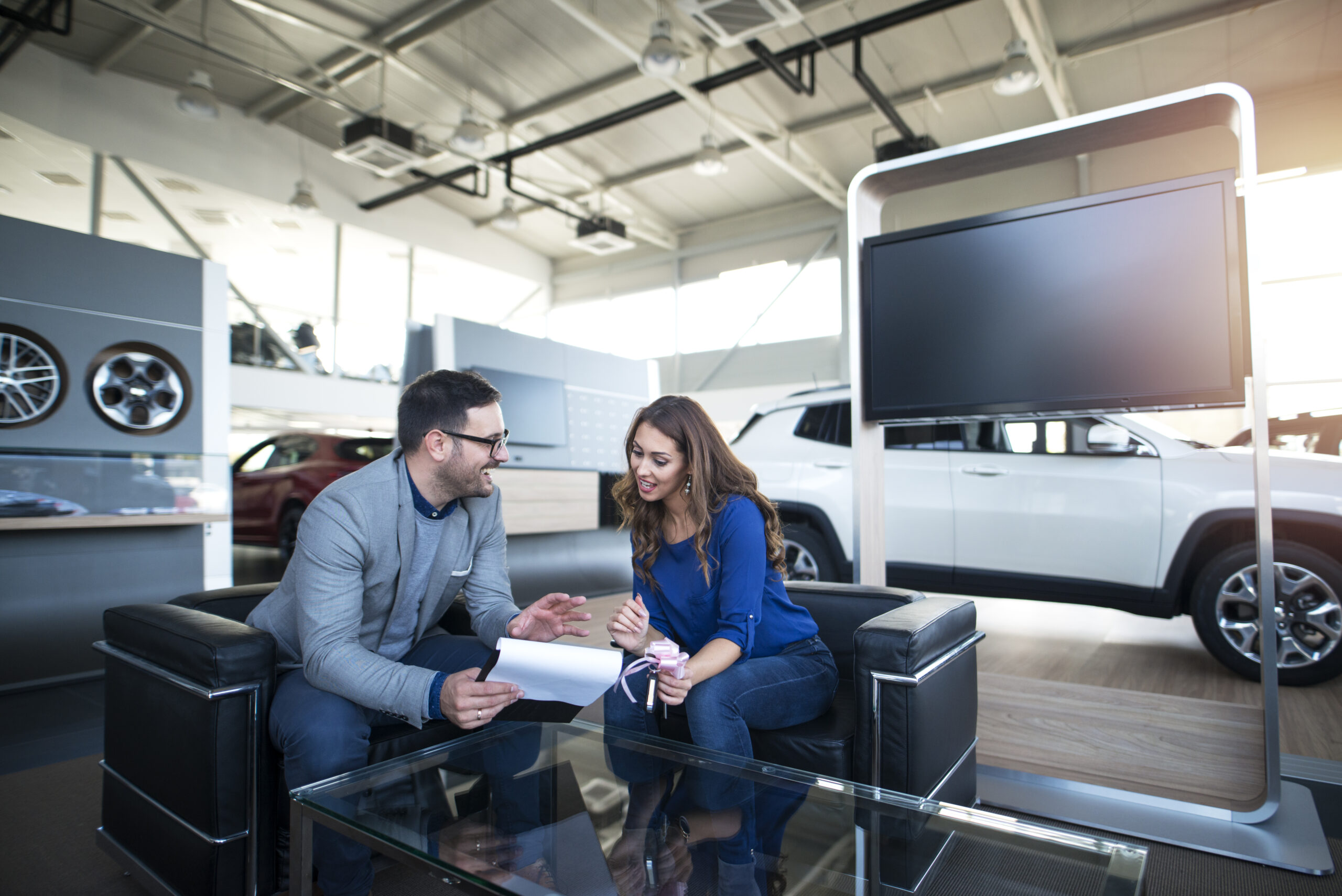 People at vehicle dealership buying new car.